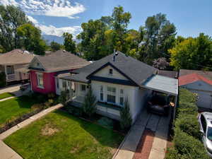 Bungalow-style house featuring a front yard, an attached carport, driveway, and roof with shingles