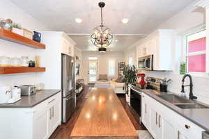 Kitchen featuring a quartz countertops, floating shelves, new(er) cabinetry and stainless steel appliances.