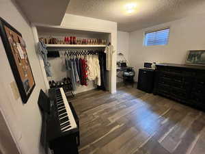 Bedroom with a textured ceiling, dark wood-style floors, and a closet