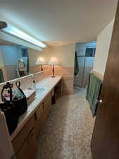 Bathroom featuring tile walls, wainscoting, and vanity