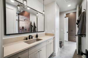 Bathroom with a shower stall, toilet, recessed lighting, concrete flooring, and vanity