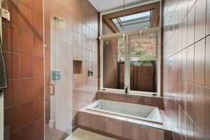 Bathroom featuring a skylight, a garden tub, and tile walls