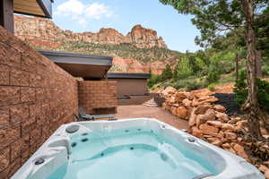 View of swimming pool with a patio, a mountain view, and an outdoor hot tub
