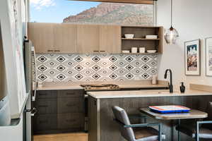 Kitchen featuring a sink, stainless steel range with gas stovetop, a breakfast bar, light countertops, and hanging light fixtures