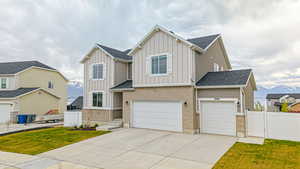 View of front of property featuring board and batten siding, fence, a mountain view, a front yard, and concrete driveway