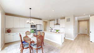 Kitchen featuring stainless steel appliances, backsplash, a sink, visible vents, and a notable chandelier