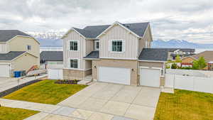 Modern farmhouse featuring fence, driveway, board and batten siding, and a mountain view