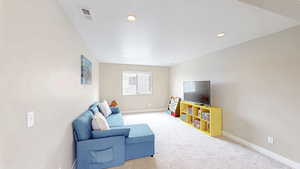 Carpeted living room with recessed lighting, visible vents, and baseboards