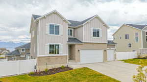 View of front of home with driveway, a garage, board and batten siding, and fence