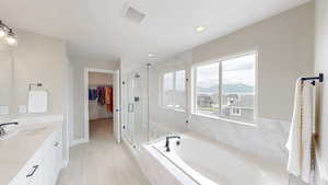 Bathroom featuring visible vents, a marble finish shower, a bath, vanity, and a walk in closet