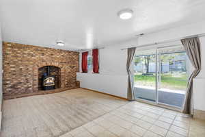 Unfurnished living room with a textured ceiling, a wood stove, visible vents, baseboards, and tile patterned flooring