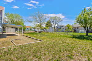 View of yard featuring an outdoor structure, fence, a storage shed, a residential view, and central AC unit