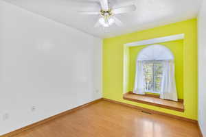 Third bedroom featuring baseboards, visible vents, wood finished floors, and a ceiling fan