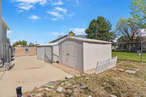 View of shed featuring fence and a gate