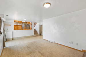 Unfurnished living room with tile patterned floors, stairway, visible vents, and a textured ceiling