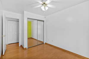 Unfurnished bedroom with baseboards, light wood-type flooring, a ceiling fan, and a closet