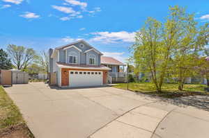 Tri-level home with concrete driveway, a chimney, a shed, an outbuilding, and an attached garage