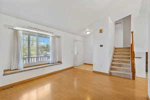 Interior space featuring baseboards, visible vents, wood finished floors, and stairs