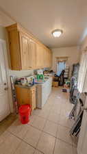 Upstairs laundry room with cabinet space, washer and clothes dryer, and light tile patterned floors