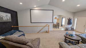 Carpeted living area with baseboards, arched walkways, vaulted ceiling, and recessed lighting