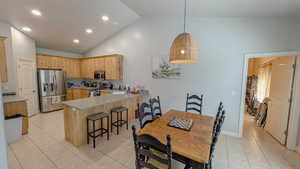 Kitchen with light brown cabinets, a kitchen breakfast bar, light tile patterned flooring, a peninsula, and appliances with stainless steel finishes