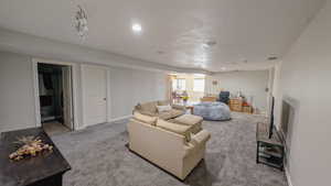 Carpeted basement living room with visible vents, baseboards, and recessed lighting
