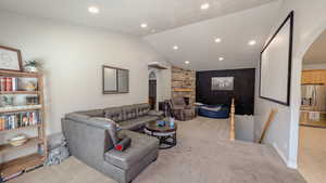 Living area featuring lofted ceiling, carpet, arched walkways, and recessed lighting