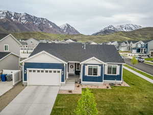 Ranch-style house featuring a front yard, a garage, a residential view, a mountain view, and concrete driveway