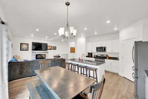 Dining room featuring a fireplace, light wood-style floors, recessed lighting, and a chandelier