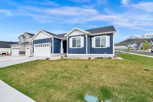 View of front of home featuring a mountain view, driveway, a front yard, and an attached garage