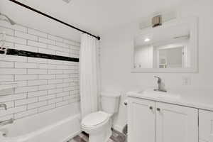 Full bathroom featuring shower / bath combo, vanity, toilet, visible vents, and baseboards