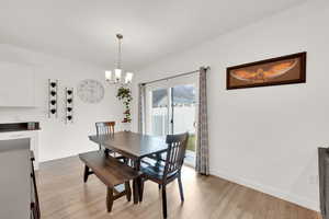 Dining space featuring light wood-style flooring, a notable chandelier, and baseboards