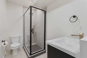 Bathroom featuring toilet, a shower stall, and vanity