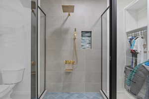 Bathroom with a spacious closet, a shower stall, and toilet