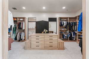 Walk in closet featuring visible vents and light colored carpet