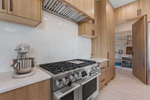 Kitchen featuring range with two ovens, custom exhaust hood, modern cabinets, and light countertops