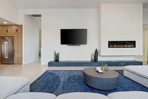 Living room with wood finished floors, recessed lighting, a warm lit fireplace, and baseboards