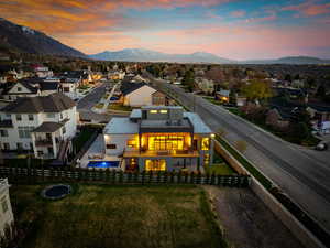 Back of house at dusk featuring a fenced backyard, a balcony, a mountain view, and a fenced in pool