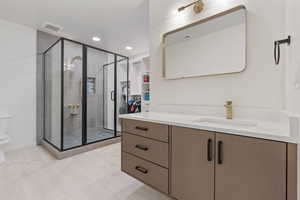 Bathroom with visible vents, a stall shower, toilet, and vanity