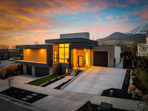 Contemporary house with concrete driveway, a garage, stucco siding, and a mountain view