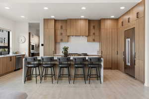 Kitchen featuring appliances with stainless steel finishes, light wood-style floors, light countertops, and custom range hood