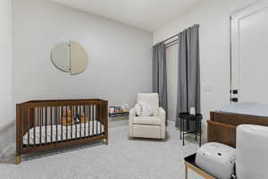 Bedroom featuring a crib, carpet flooring, and baseboards