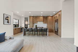 Kitchen featuring a breakfast bar, open floor plan, brown cabinets, and stainless steel appliances