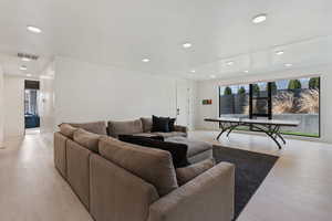 Living area with a wealth of natural light, visible vents, light wood-type flooring, and recessed lighting