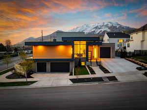 Modern home with a mountain view, fence, and concrete driveway