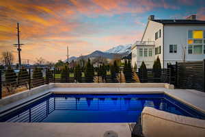 Pool at dusk with a mountain view, fence, and a fenced in pool