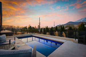 Pool at dusk with a mountain view and a fenced backyard