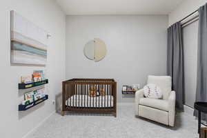 Carpeted bedroom featuring a nursery area and baseboards