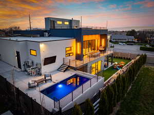 Back of property featuring a balcony, a patio area, a fenced in pool, stucco siding, and fence