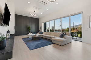 Living room featuring recessed lighting, an inviting chandelier, a wealth of natural light, a mountain view, and wood finished floors